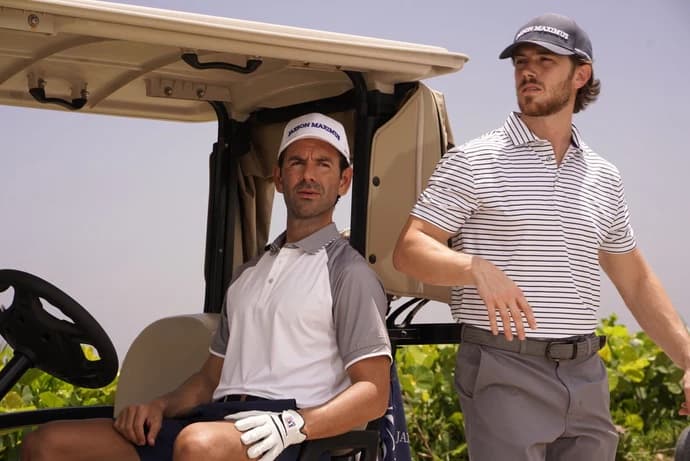 Two golfers at a cart in Jaxson Maximus caps and performance polos